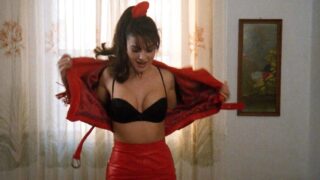 Monica Bellucci unzipping and taking off her red leather jacket to reveal cleavage in a black bra as a couple guys first look on and then turn around to face away from her